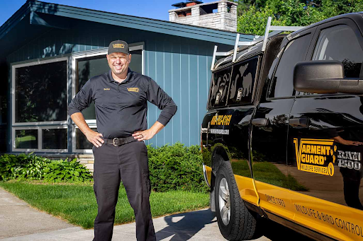 Varment Guard wildlife technician standing next to a service truck